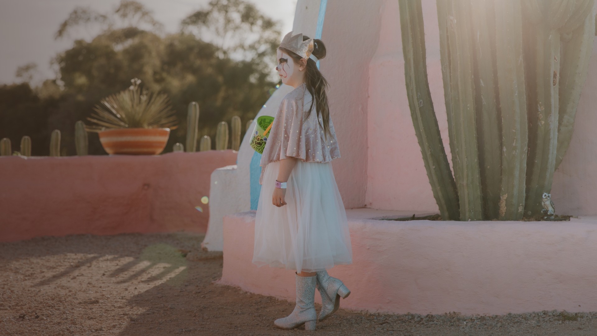 A child in Halloween costume beside the pink wall and giant cacti at Cactus Country.